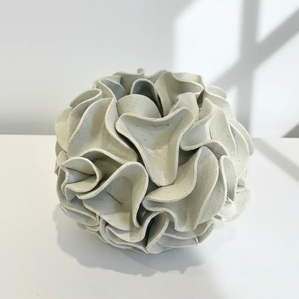 Decorative ceramic vase with ruffled texture on natural white clay