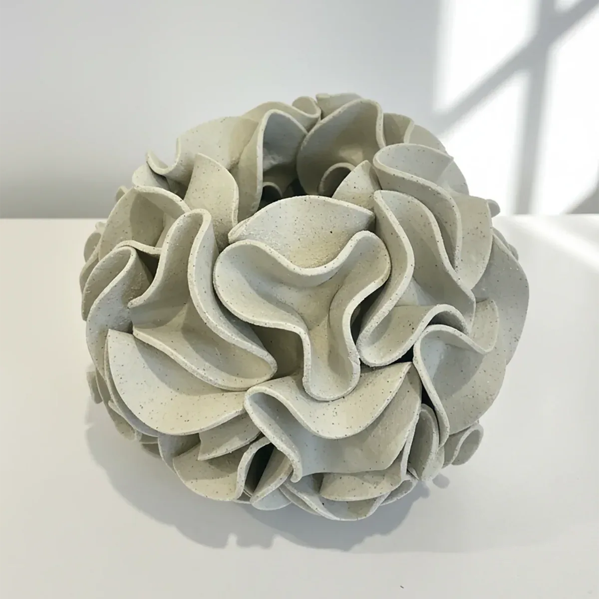 Decorative ceramic vase with ruffled texture on natural white clay