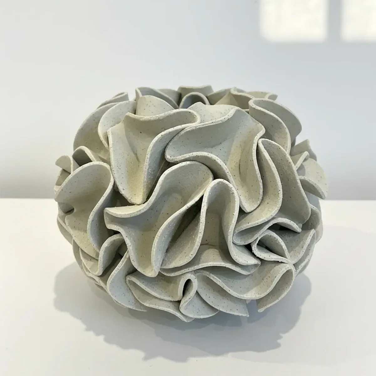 Decorative ceramic vase with ruffled texture on natural white clay