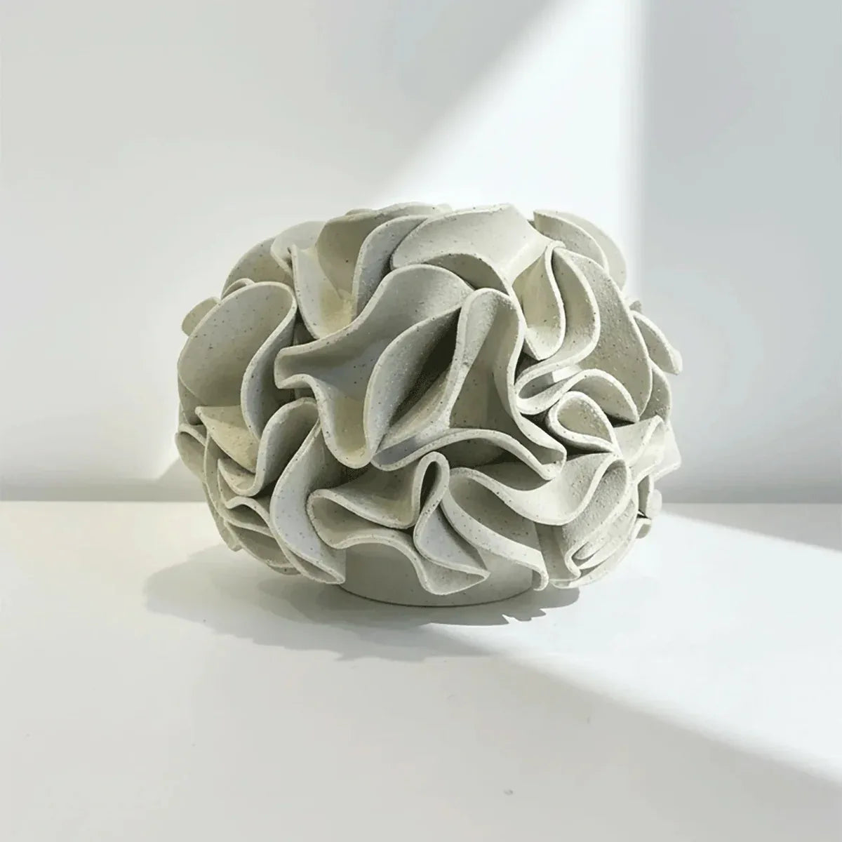 Decorative ceramic vase with ruffled folds on natural white clay