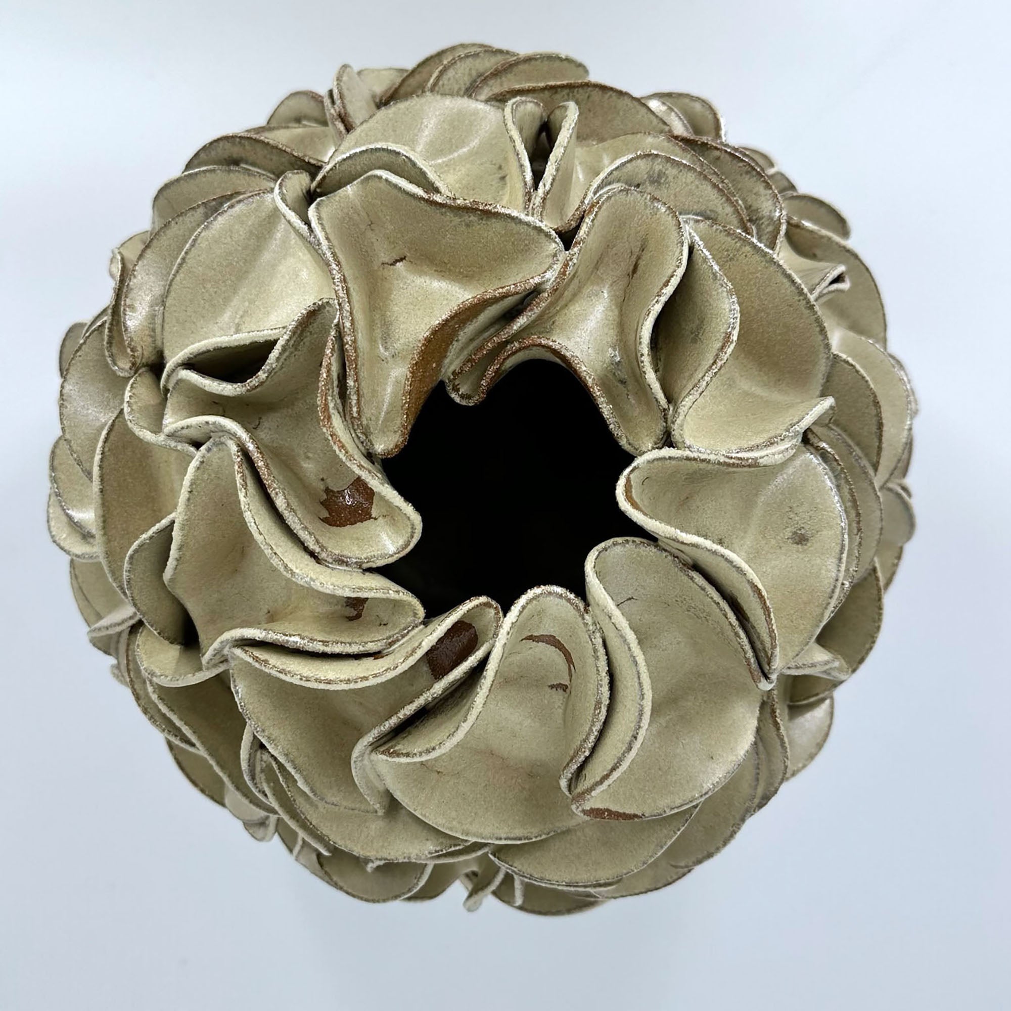 A sculptural egg-shaped decorative vase in melted mint glaze, overlapping petal-like surface folds, photographed from directly above.