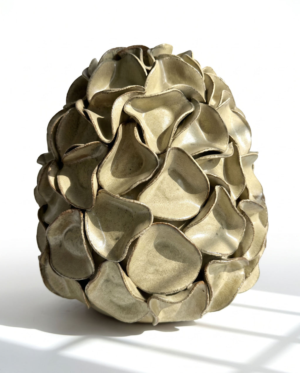 A sculptural egg-shaped decorative vase in melted mint glaze, overlapping petal-like surface folds.