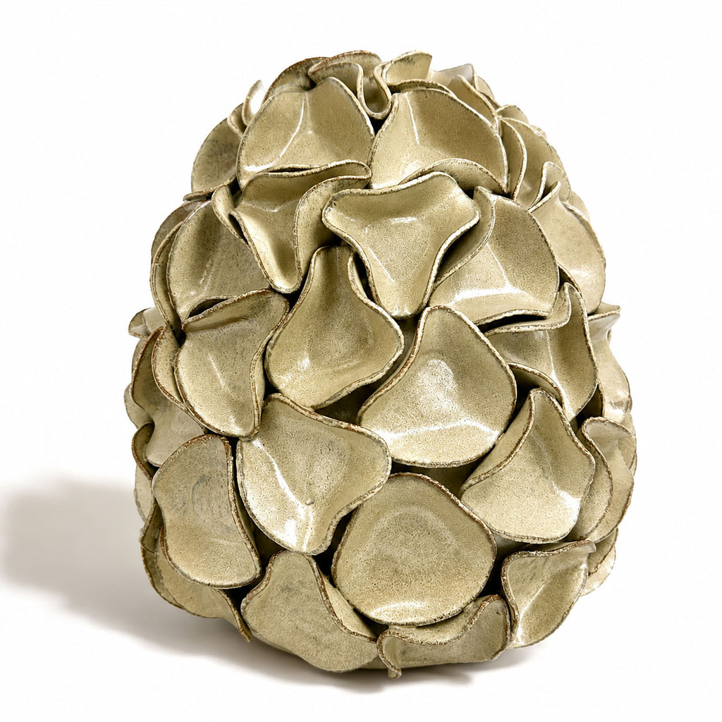 A very large decorative ceramic sculpture resembling a stylized egg, composed of overlapping petal-like scales, shown on a plain white background. By Polly Barton