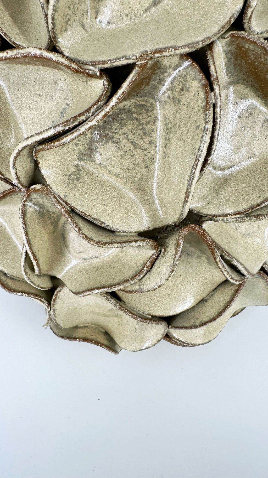 A close-up of a gold minty green textured ceramic with layered, organic scalloped petals.