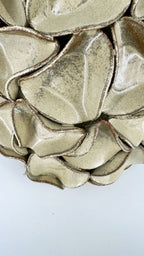 A close-up of a gold minty green textured ceramic with layered, organic scalloped petals.