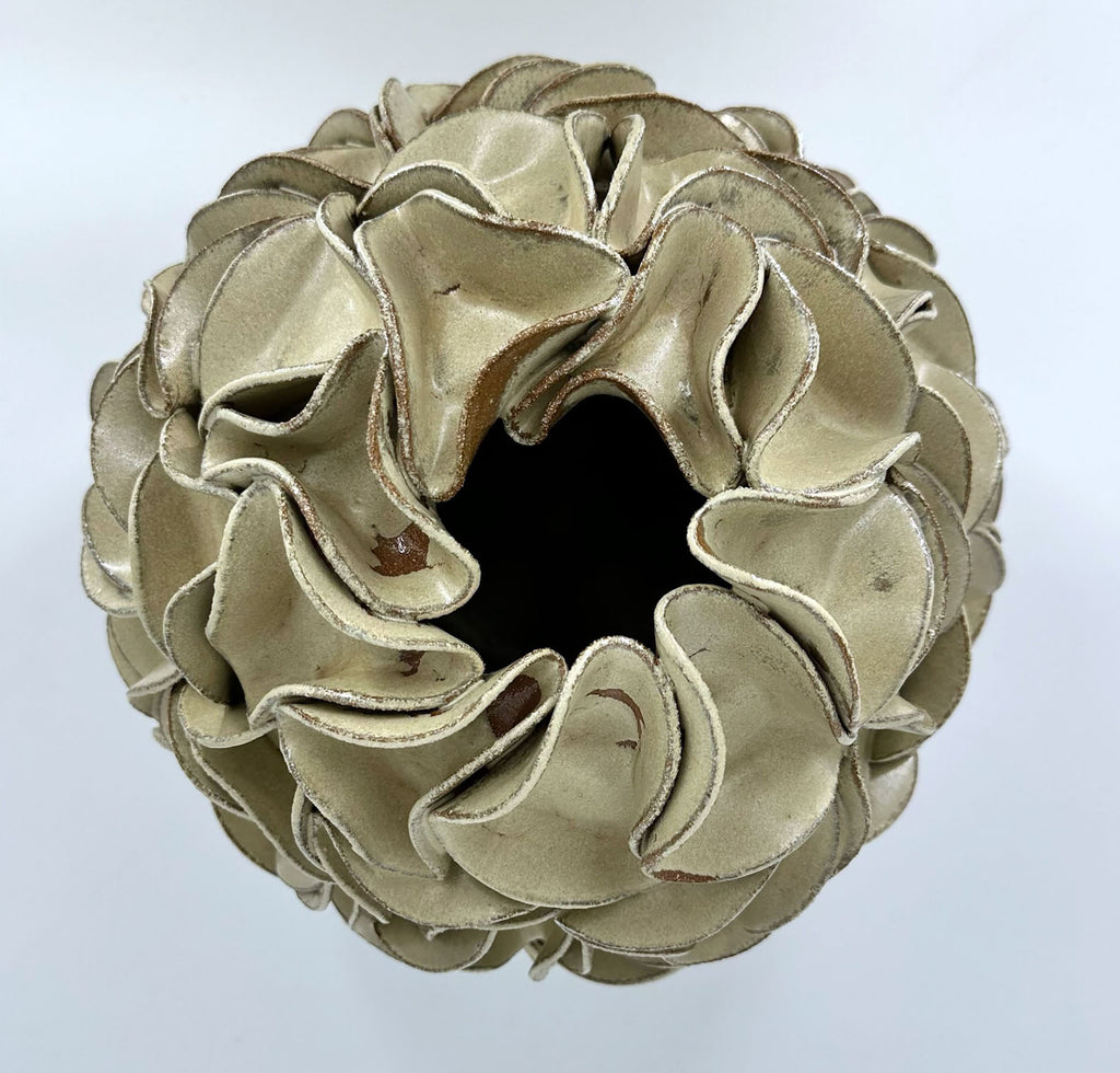A sculptural egg-shaped decorative vase in melted mint glaze, overlapping petal-like surface folds, photographed from directly above.