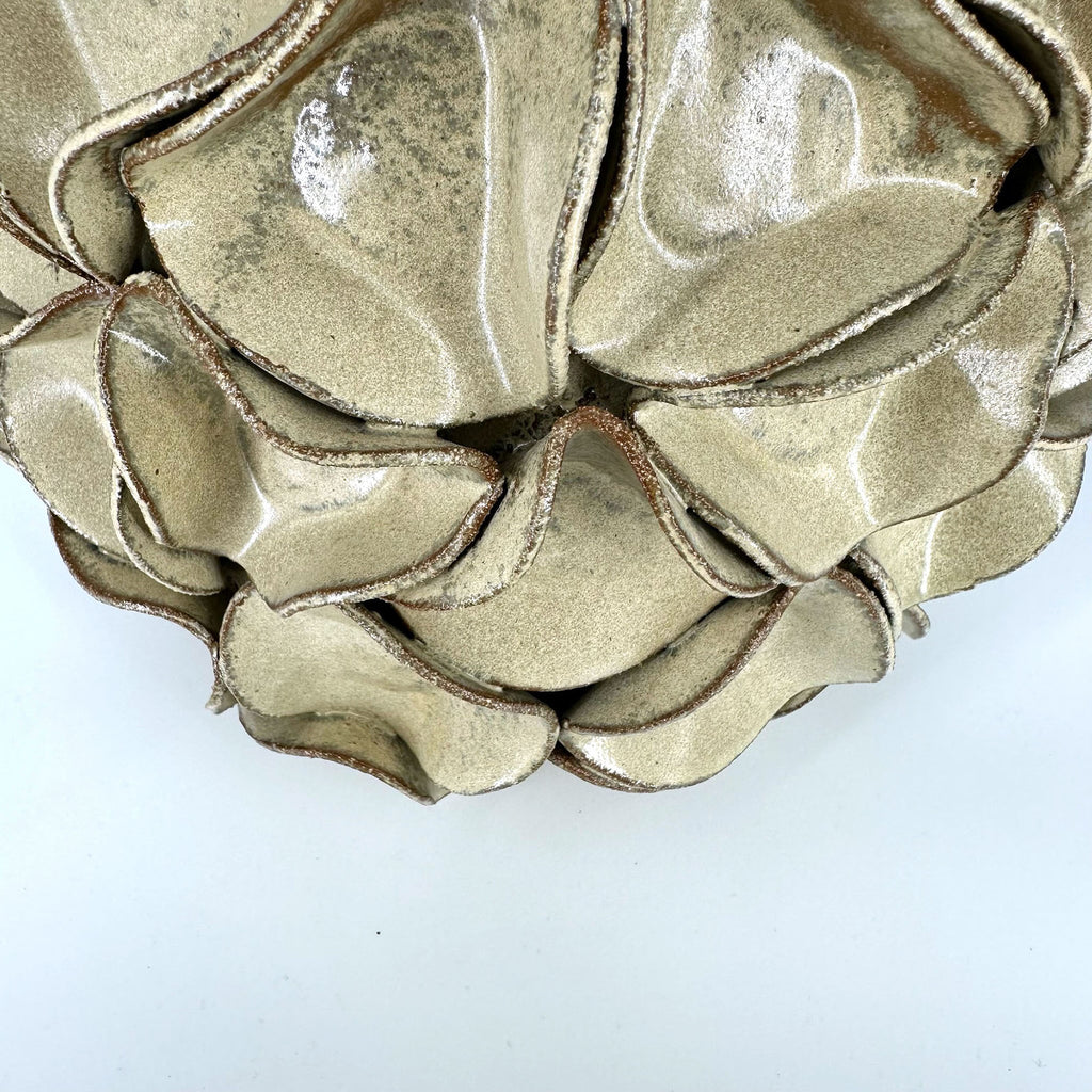 A close-up of a ceramic vase with a textured, ruffled petal-like design.