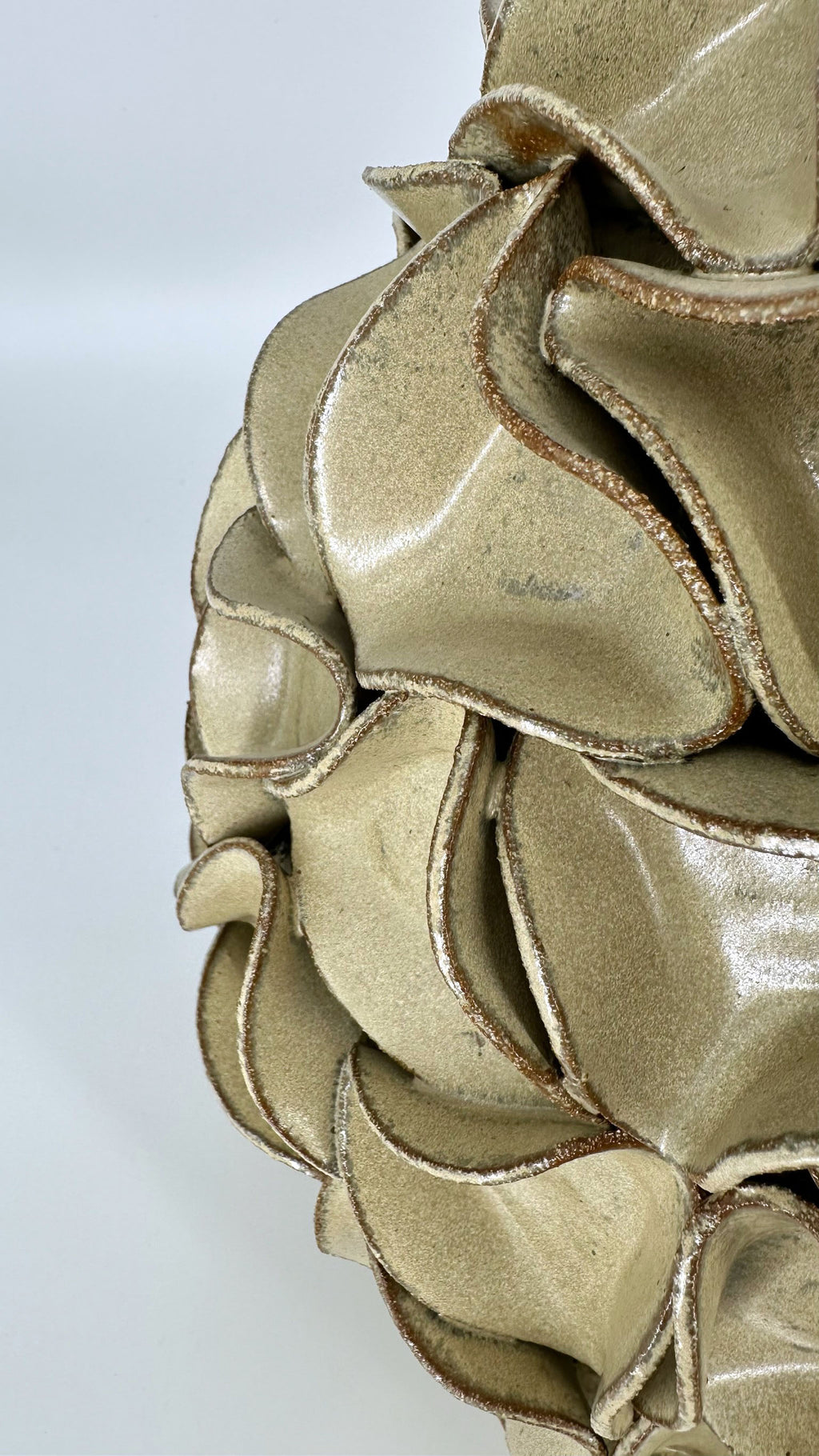 A close-up of gold-mint-green ruffled decorative vase, showing layered scalloped edges with a shimmering finish.