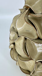 A close-up of gold-mint-green ruffled decorative vase, showing layered scalloped edges with a shimmering finish.