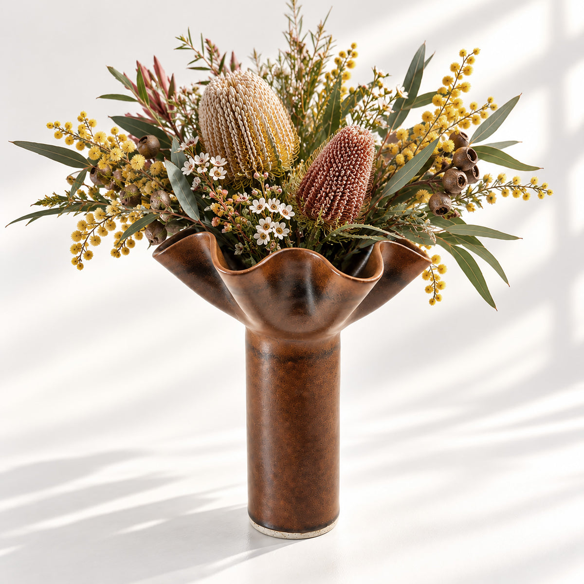 Hand-built ceramic flower vase in a rich chocolate brown glaze, featuring a sculptural ruffled rim and elegant cylindrical form