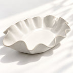 Hand-built white ceramic serving bowl featuring a sculptural wave rim, soft curves and flat base