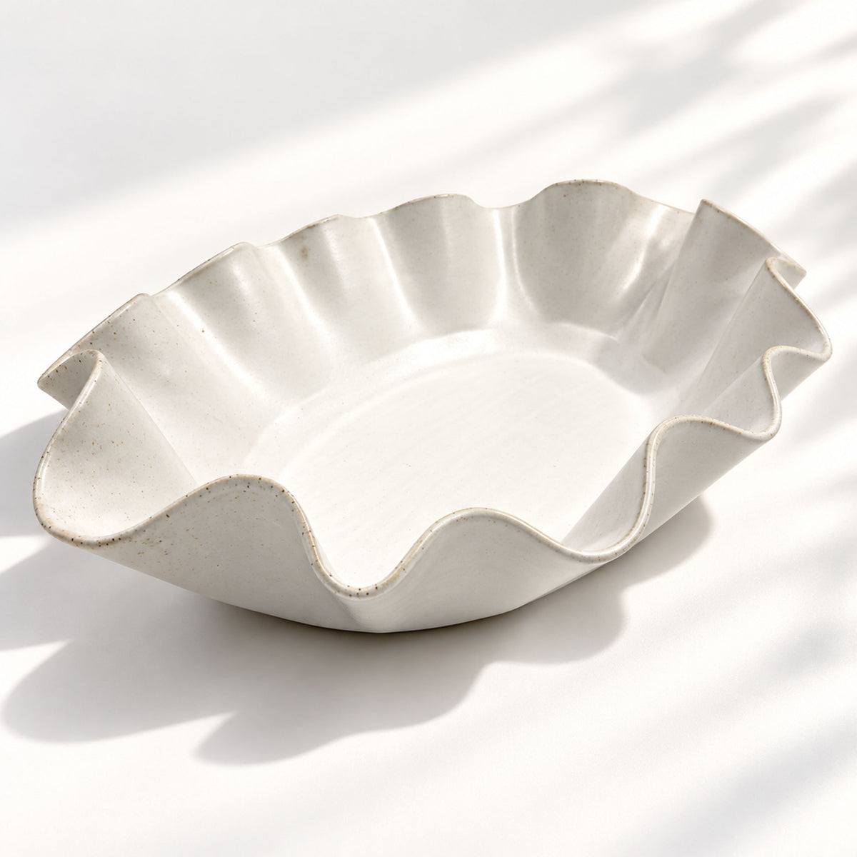Hand-built white ceramic serving bowl featuring a sculptural wave rim, soft curves and flat base