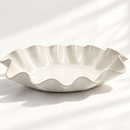 Hand-built white ceramic serving bowl featuring a sculptural wave rim, soft curves and flat base