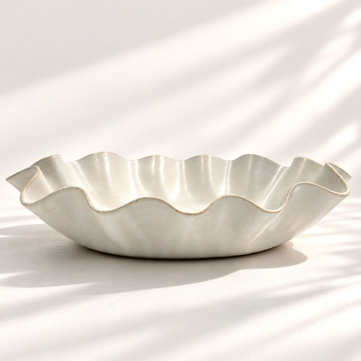 Large handmade stoneware serving bowl in a white satin glaze, with an elegant undulating rim inspired by coastal waves