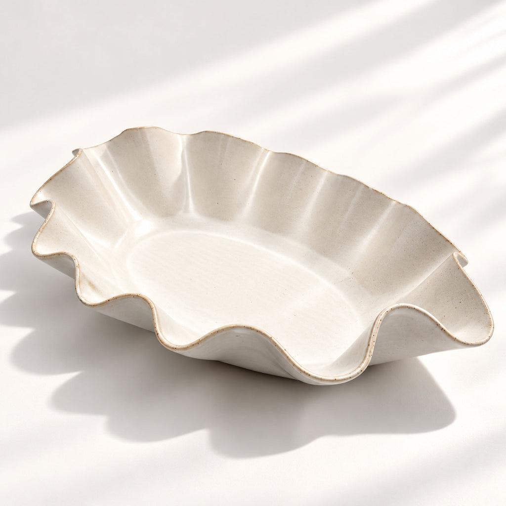 Large handmade stoneware serving bowl in a warm white glaze, with an elegant undulating rim inspired by coastal waves