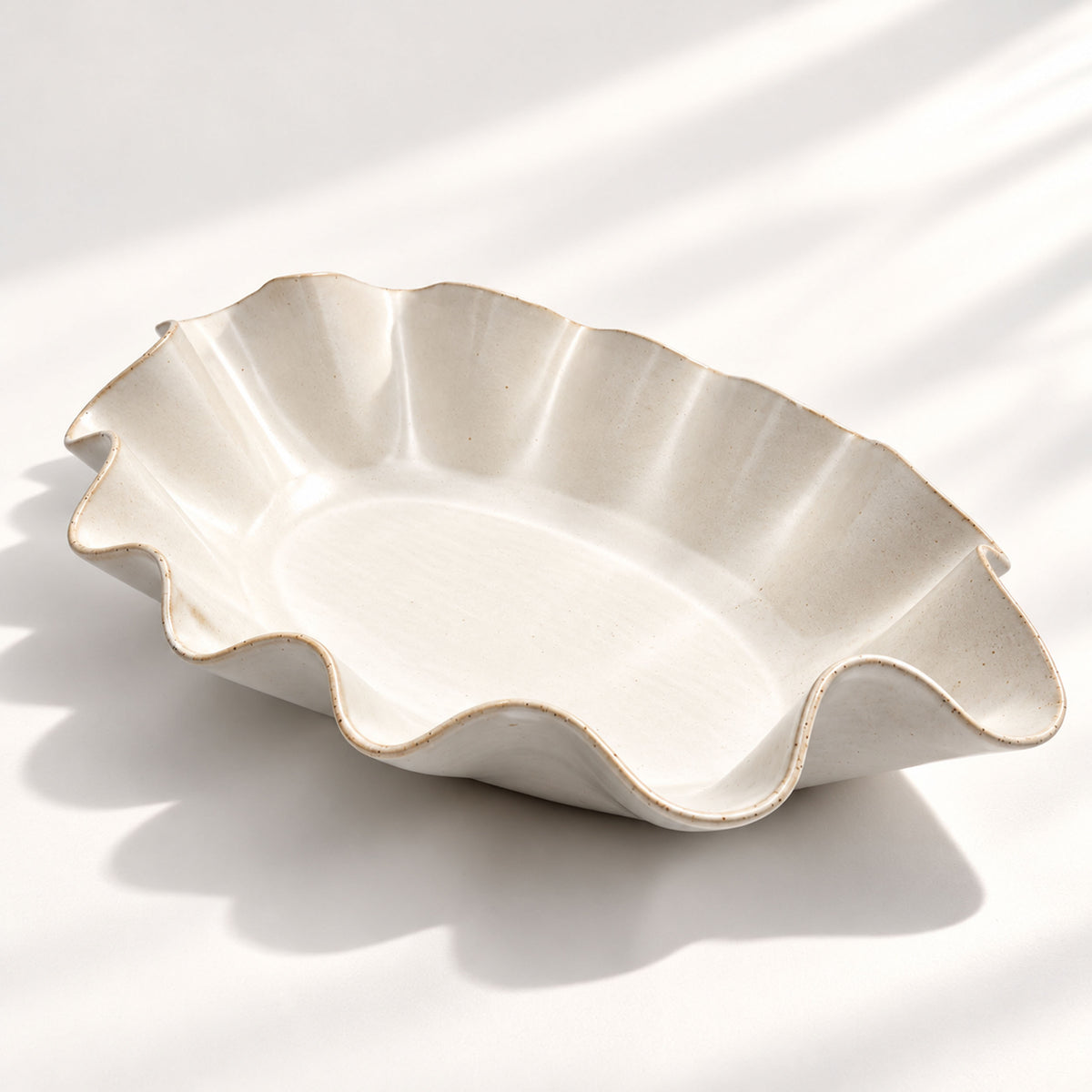 Large handmade stoneware serving bowl in a warm white glaze, with an elegant undulating rim inspired by coastal waves